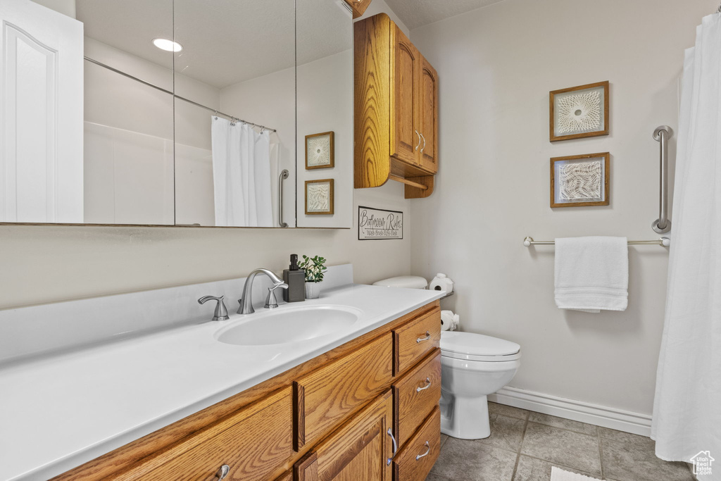 Full bathroom featuring baseboards, vanity, toilet, and a shower with shower curtain