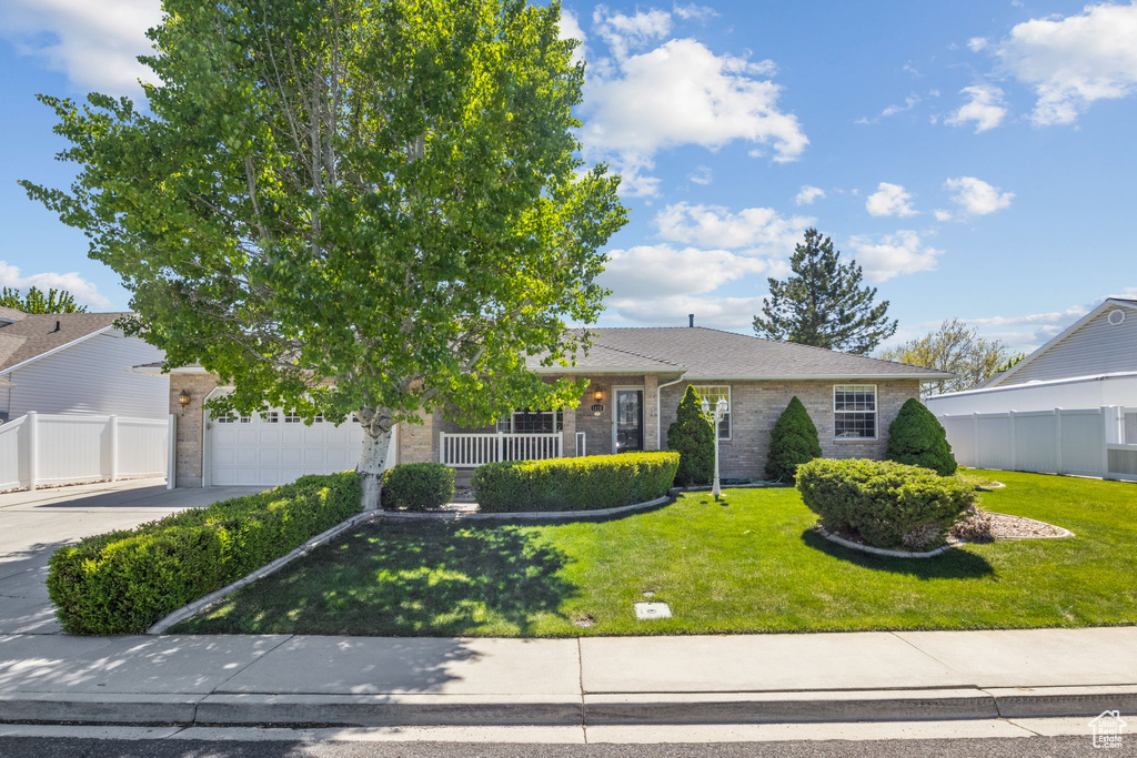 Obstructed view of property with brick siding, fence, driveway, and a garage