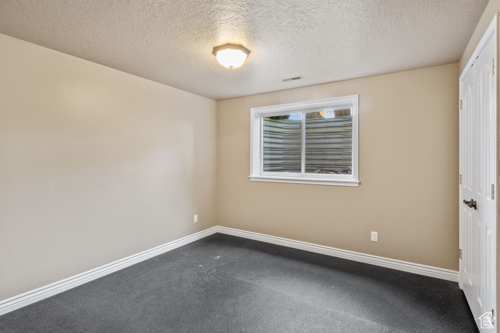 Spare room with baseboards, a textured ceiling, and visible vents