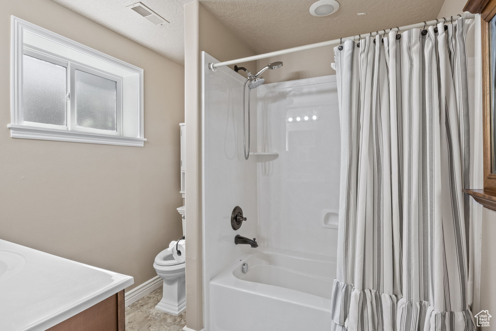 Full bathroom with vanity, toilet, shower / bath combination with curtain, baseboards, and visible vents