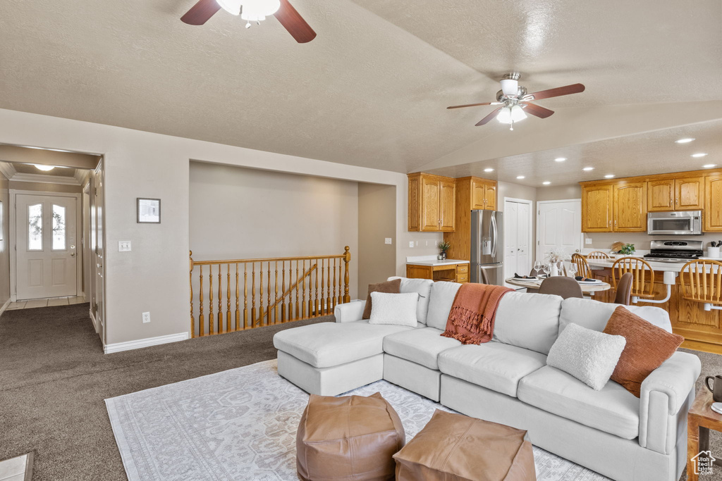 Carpeted living area with a ceiling fan, a textured ceiling, baseboards, lofted ceiling, and recessed lighting