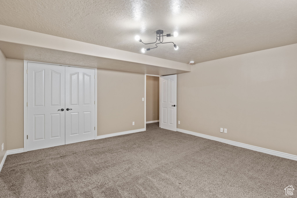 Interior space with carpet floors, a textured ceiling, baseboards, and a closet