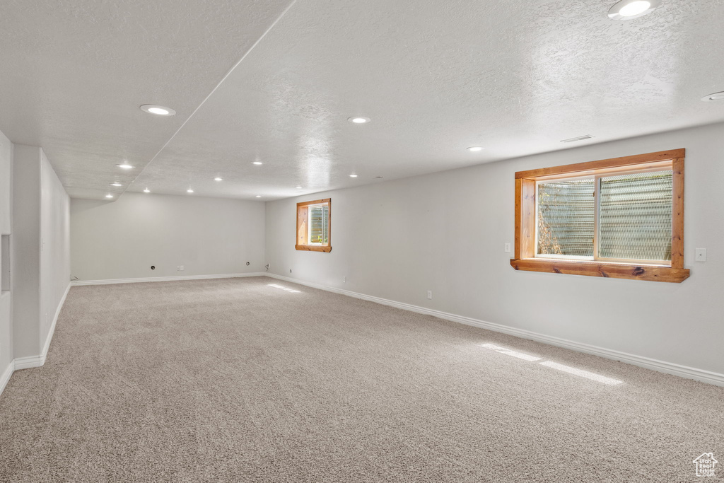 Below grade area featuring a textured ceiling, visible vents, baseboards, carpet flooring, and recessed lighting