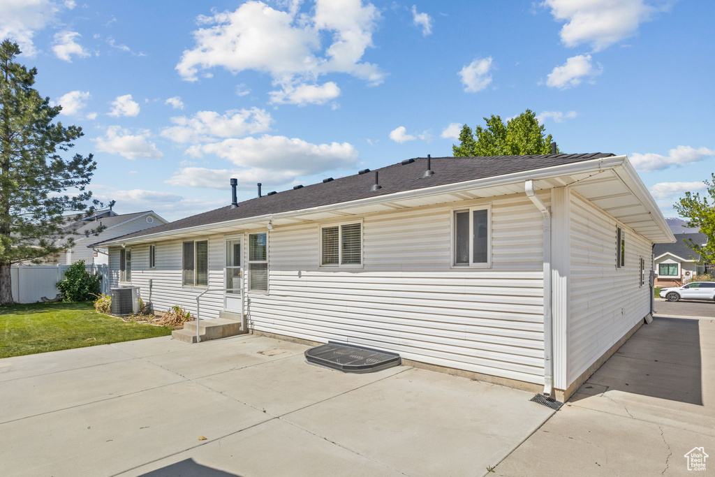 Back of property featuring central air condition unit, fence, a patio, and a yard
