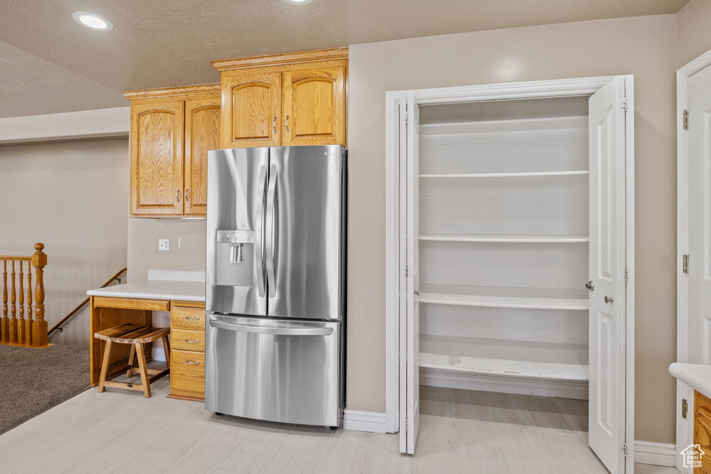Kitchen featuring light countertops, stainless steel refrigerator with ice dispenser, recessed lighting, and light brown cabinets