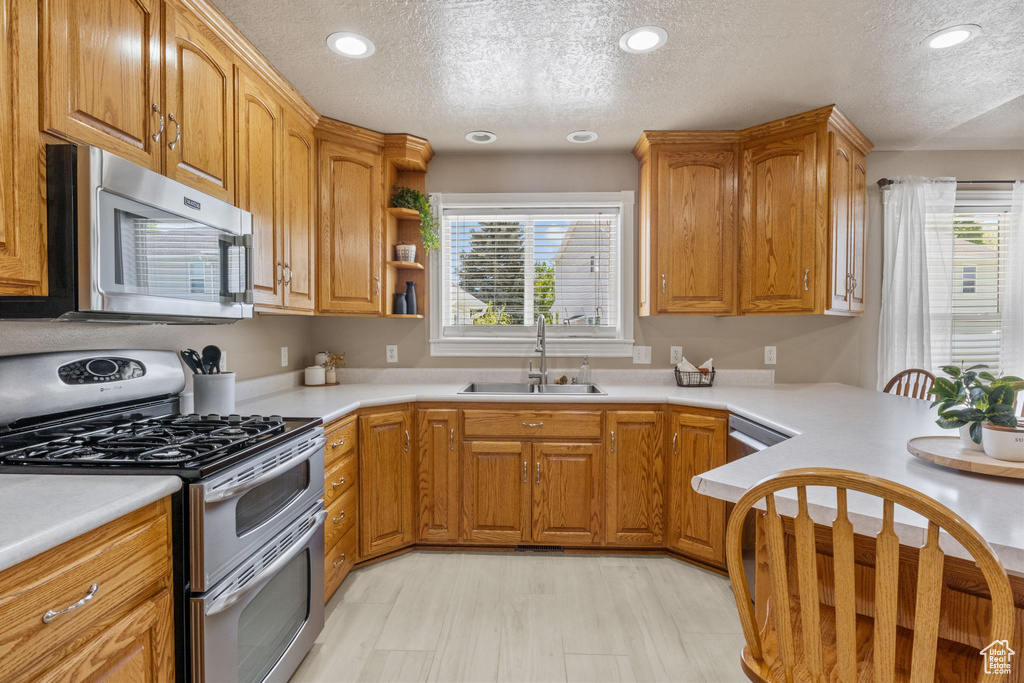 Kitchen featuring a textured ceiling, appliances with stainless steel finishes, a wealth of natural light, and a sink