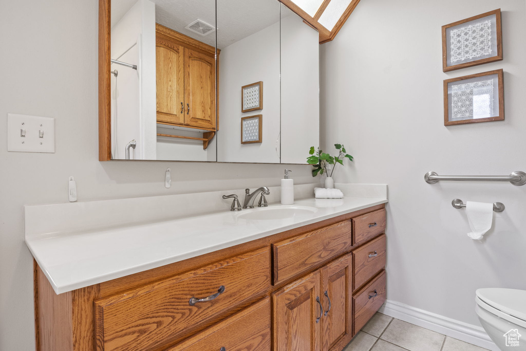 Bathroom featuring visible vents, tile patterned flooring, vanity, baseboards, and toilet