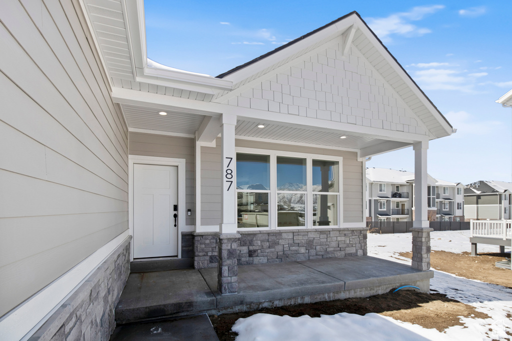 View of exterior entry with covered porch and stone siding