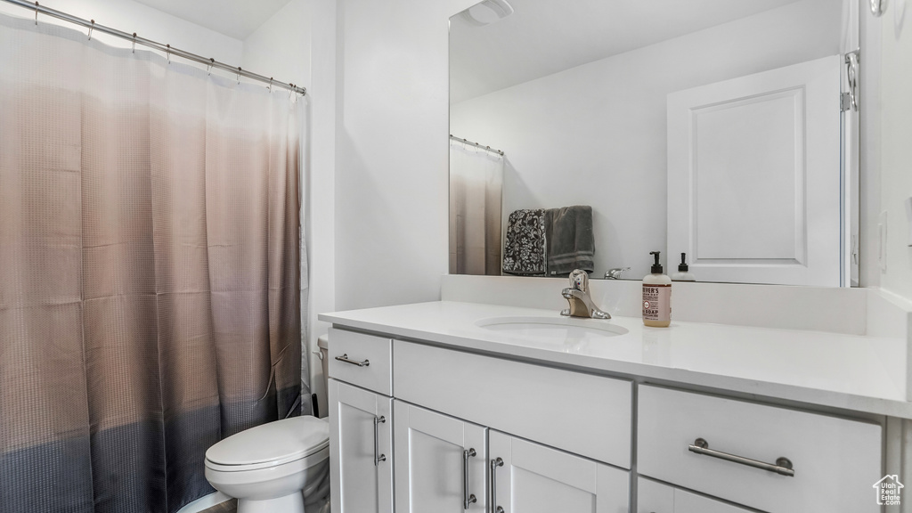 Bathroom featuring vanity, toilet, and curtained shower