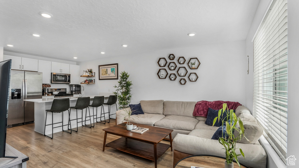 Living room featuring light wood-style floors, recessed lighting, and a wealth of natural light