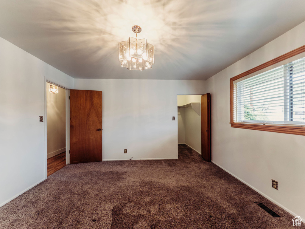 Unfurnished bedroom with baseboards, carpet flooring, a chandelier, and visible vents