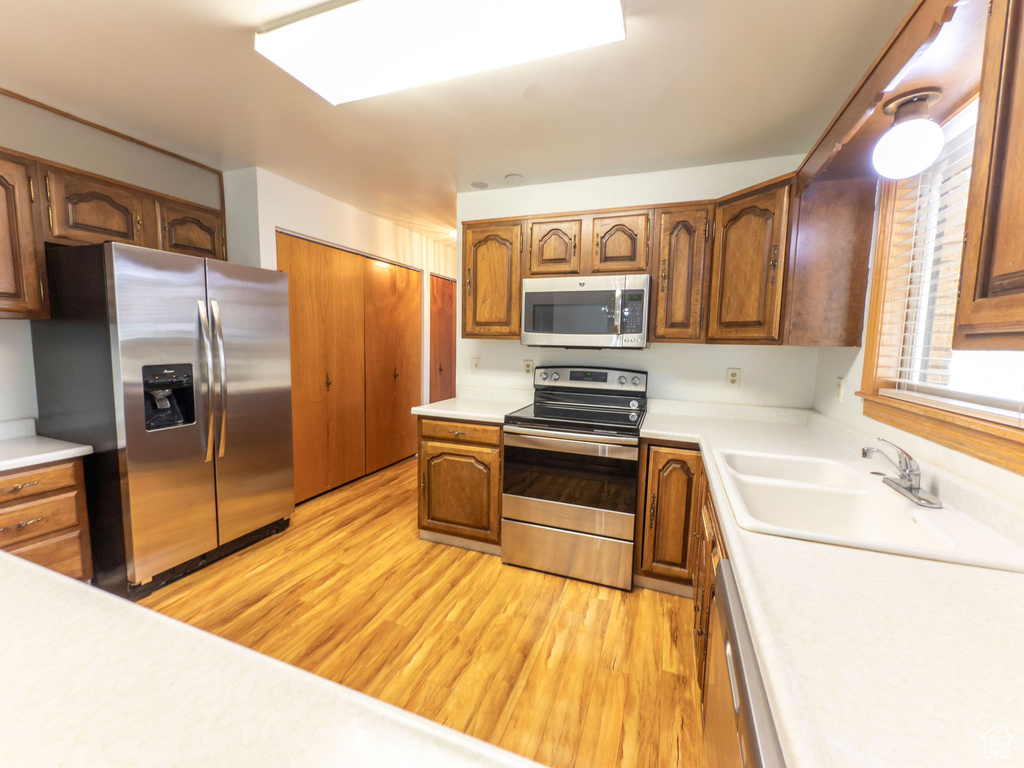 Kitchen featuring a sink, light countertops, stainless steel appliances, and light wood-style flooring