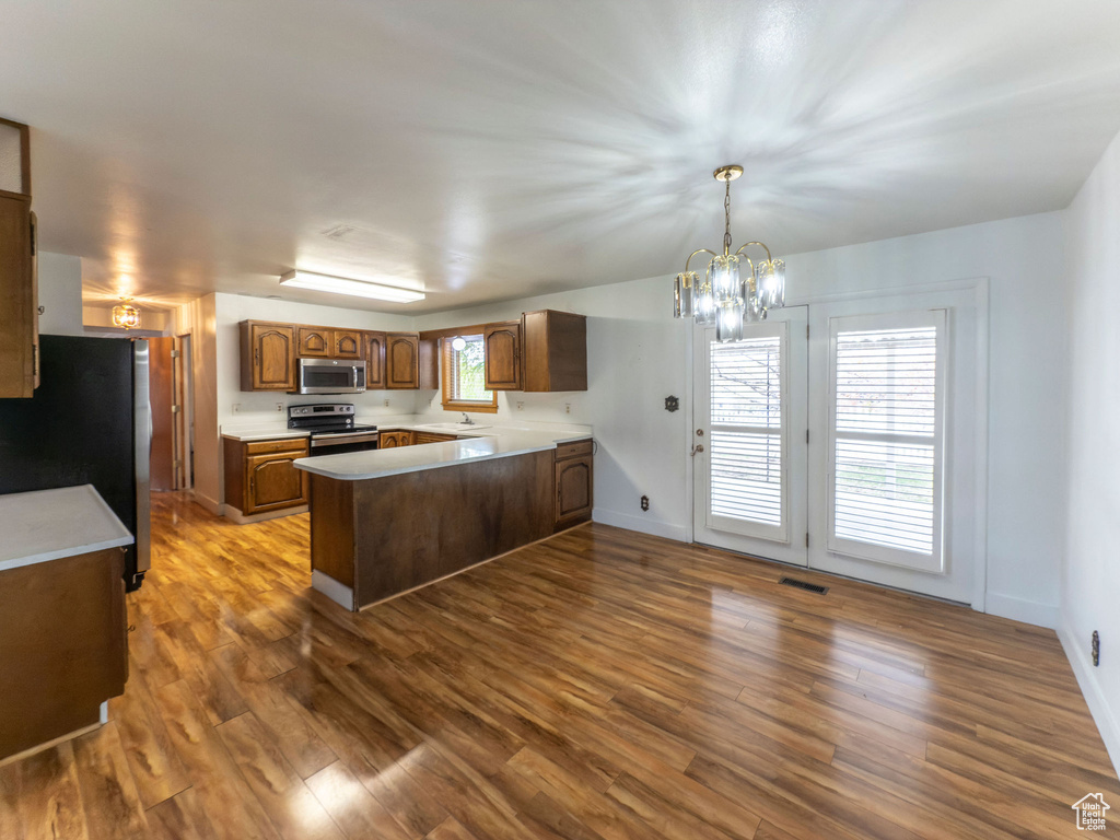 Kitchen with visible vents, dark wood-style flooring, a peninsula, light countertops, and stainless steel appliances