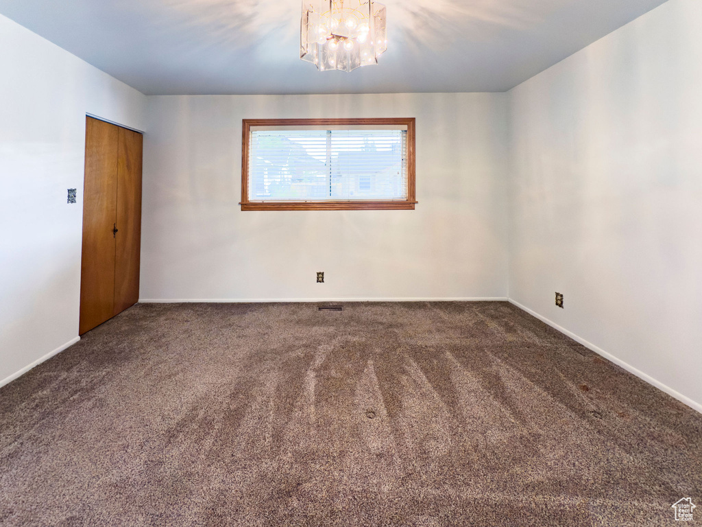 Empty room with baseboards, a chandelier, and carpet
