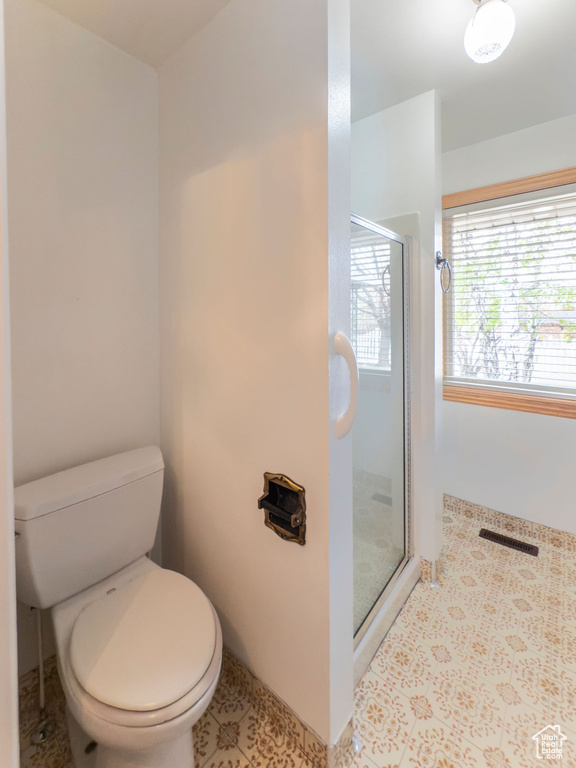 Bathroom featuring a stall shower, toilet, and visible vents