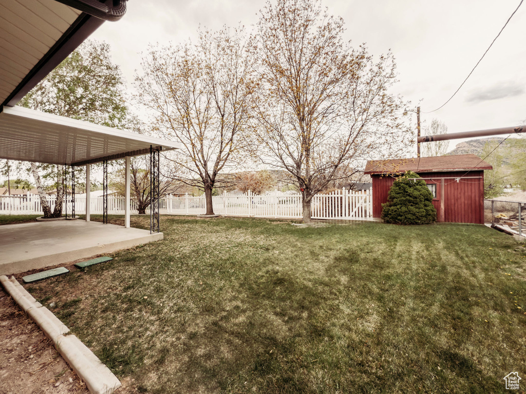 View of yard featuring a patio, fence, and an outbuilding