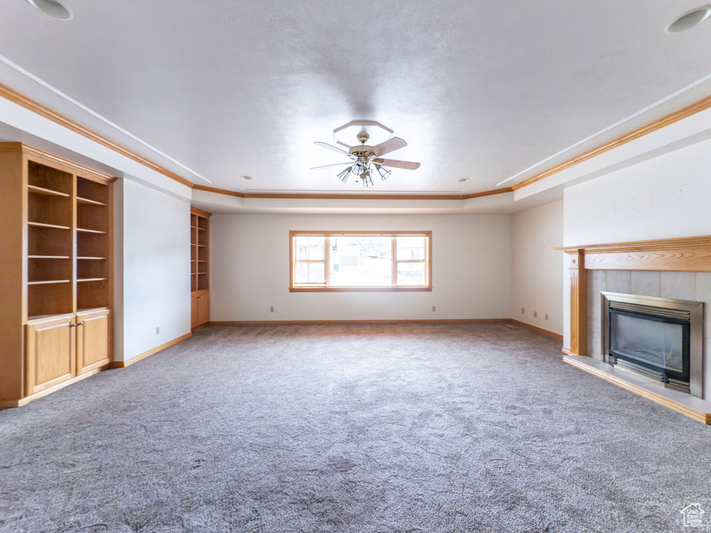 Unfurnished living room featuring a tray ceiling, ornamental molding, and carpet