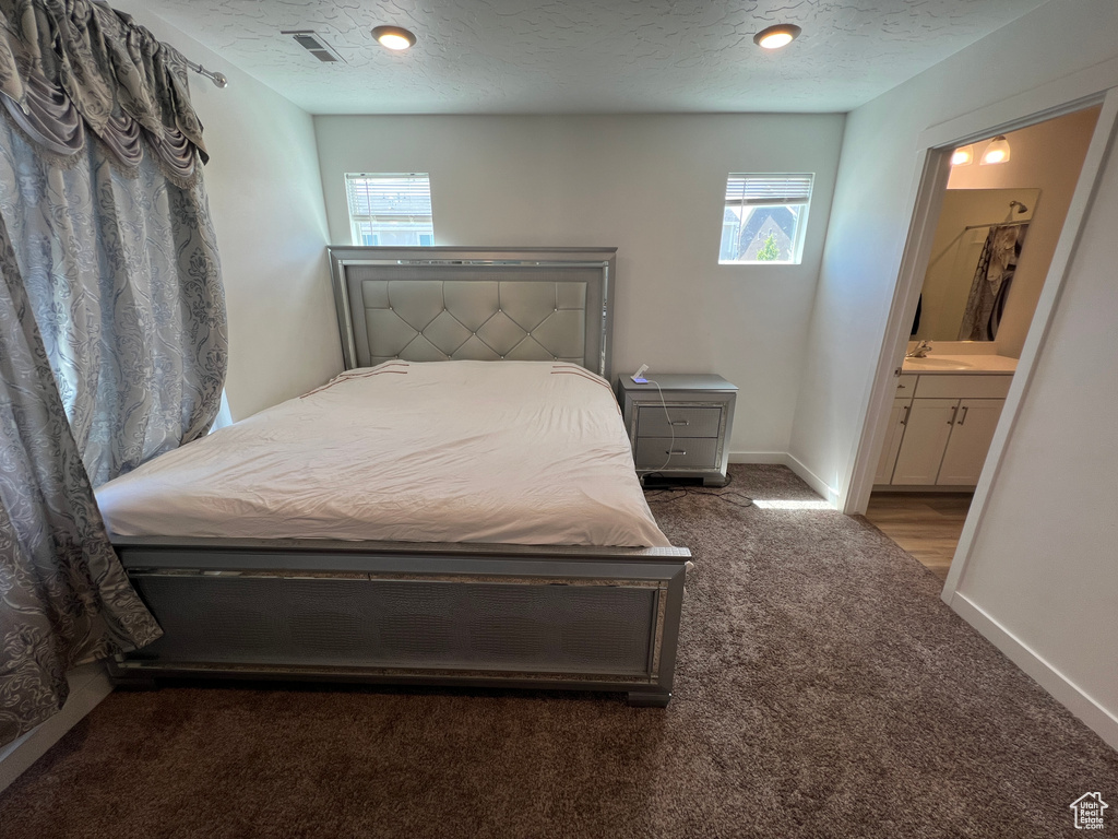Bedroom featuring multiple windows, carpet, connected bathroom, baseboards, and a textured ceiling