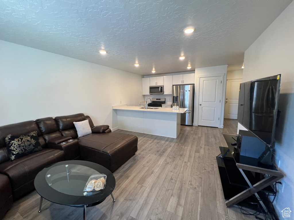 Living room featuring light wood finished floors, a textured ceiling, and recessed lighting