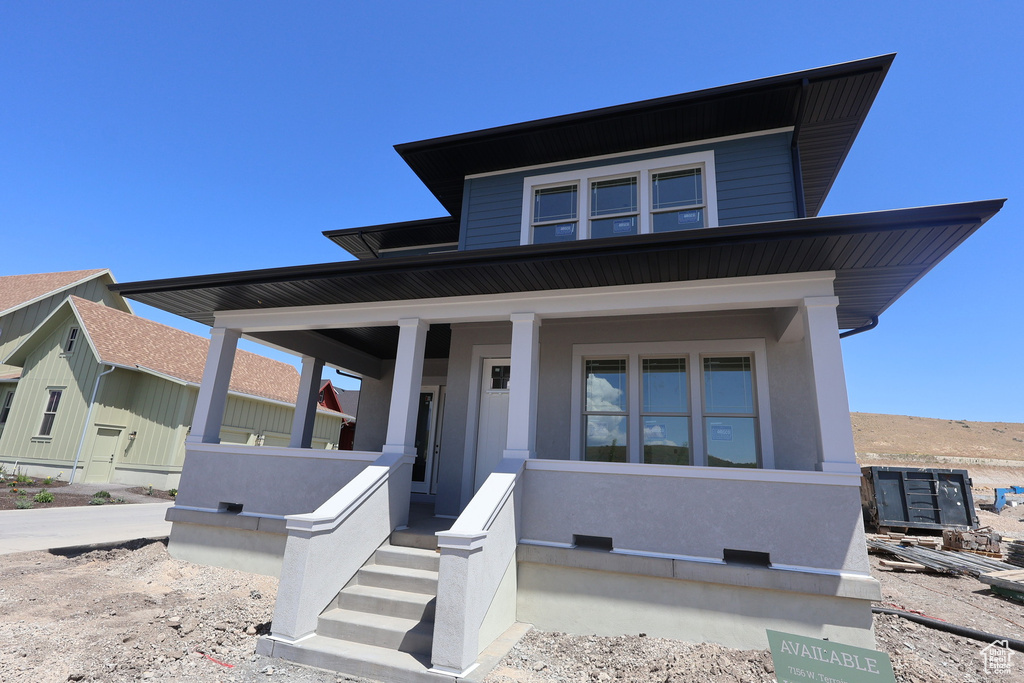 View of front of home featuring covered porch and stucco siding