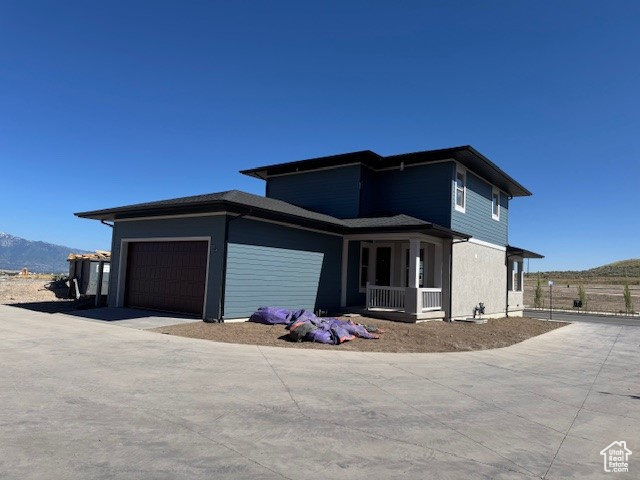 View of front of property featuring an attached garage, covered porch, and a mountain view