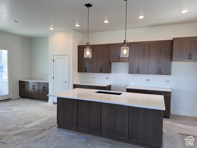 Kitchen with dark brown cabinets, decorative light fixtures, baseboards, light countertops, and recessed lighting