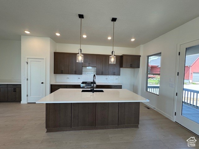 Kitchen with a sink, dark brown cabinets, backsplash, light countertops, and recessed lighting