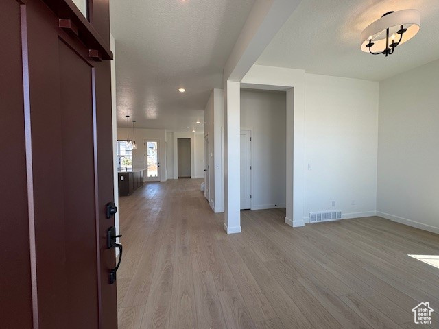 Foyer entrance with baseboards, light wood finished floors, a chandelier, and recessed lighting