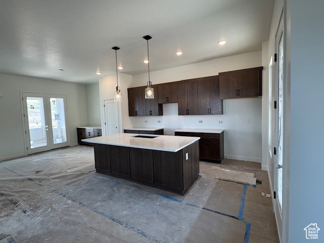 Kitchen featuring dark brown cabinets, baseboards, a kitchen island, decorative light fixtures, and recessed lighting