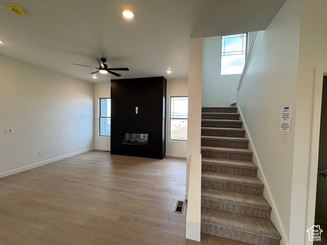Stairway featuring wood finished floors, ceiling fan, baseboards, recessed lighting, and a fireplace