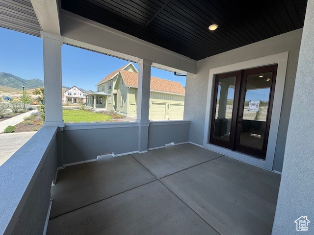 View of patio with french doors, a mountain view, and a balcony