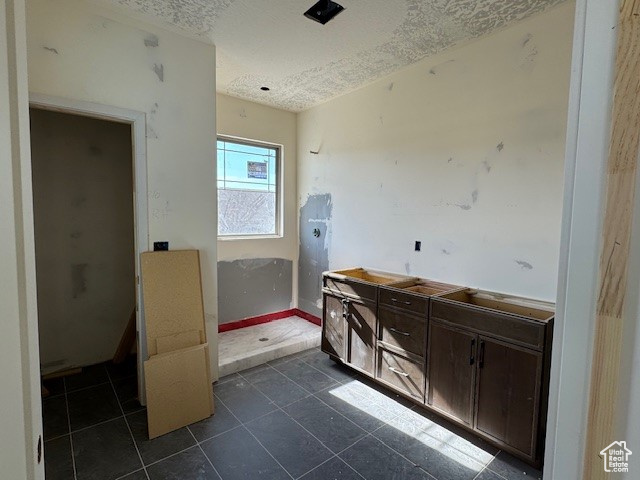Bathroom with a textured ceiling, tile patterned flooring, vanity, a shower, and baseboards