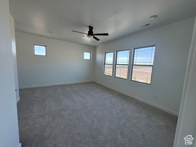 Spare room with a ceiling fan, healthy amount of natural light, baseboards, and a textured ceiling