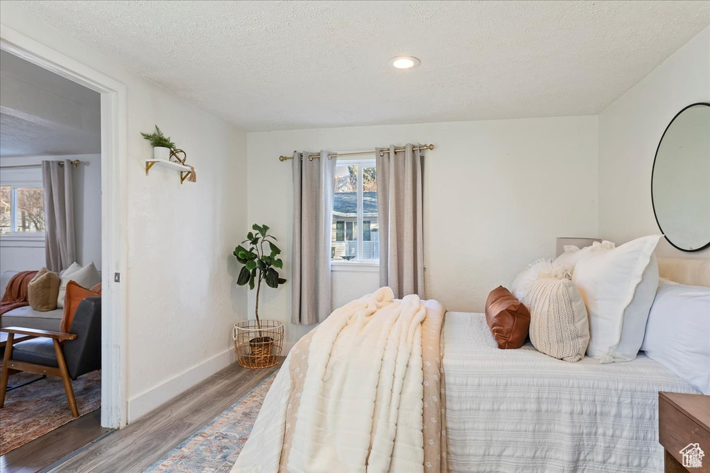 Bedroom featuring baseboards, wood finished floors, a textured ceiling, and multiple windows
