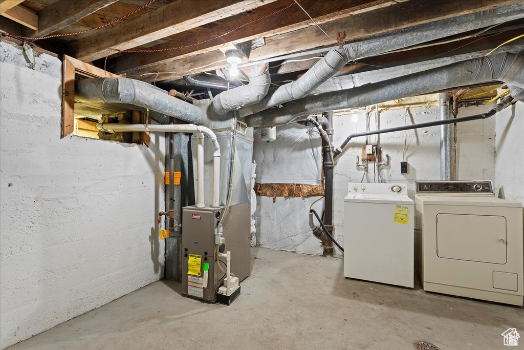 Unfinished below grade area featuring heating unit and independent washer and dryer