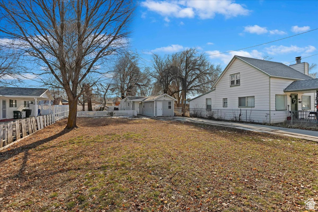 View of side of home with a residential view, an outbuilding, and fence