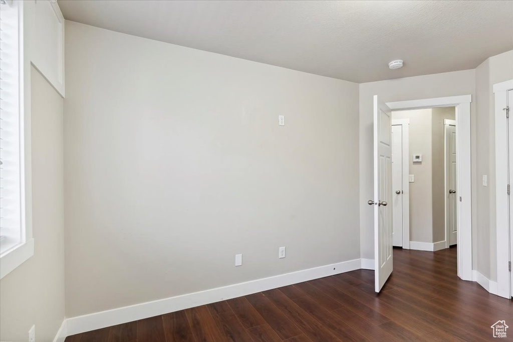Unfurnished bedroom featuring dark wood finished floors and baseboards