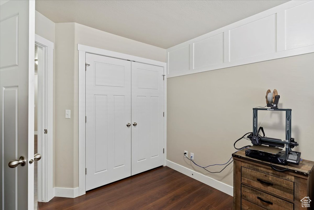 Unfurnished bedroom with dark wood-type flooring, a closet, and baseboards