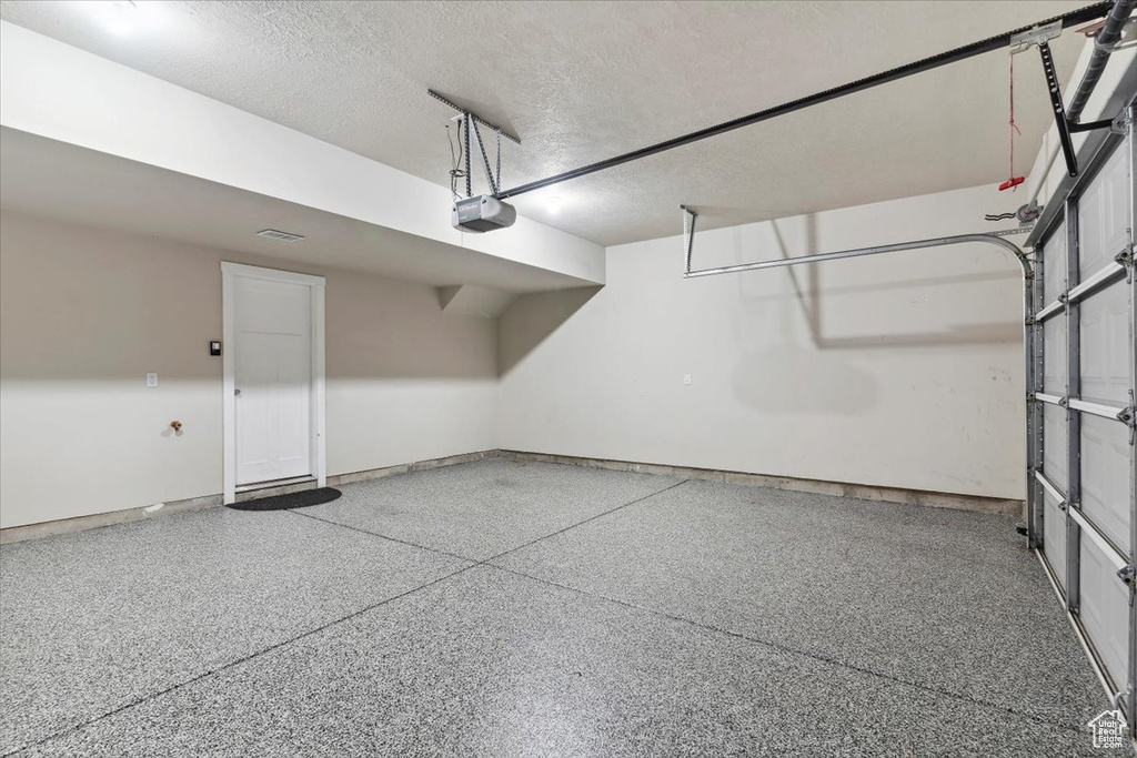 Garage featuring a garage door opener and baseboards