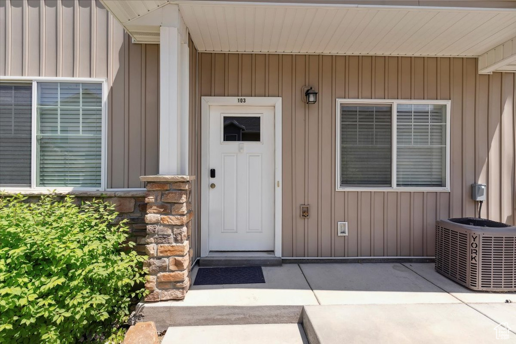 Property entrance featuring cooling unit and board and batten siding