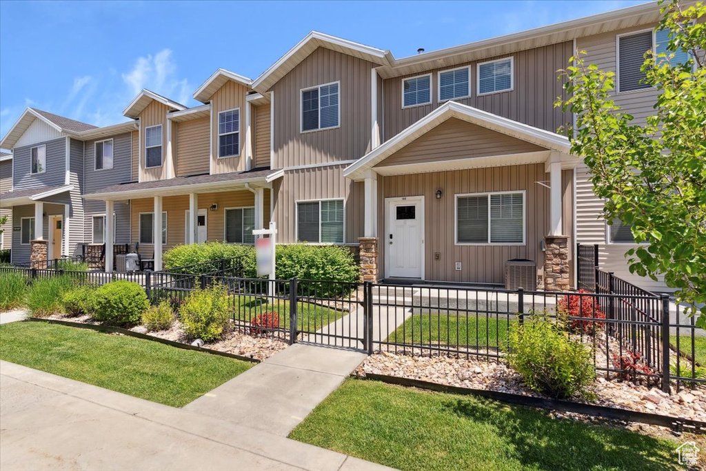 Townhome / multi-family property with board and batten siding, a fenced front yard, and covered porch