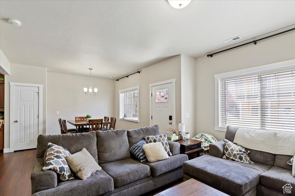 Living room with a chandelier, visible vents, and dark wood-style floors
