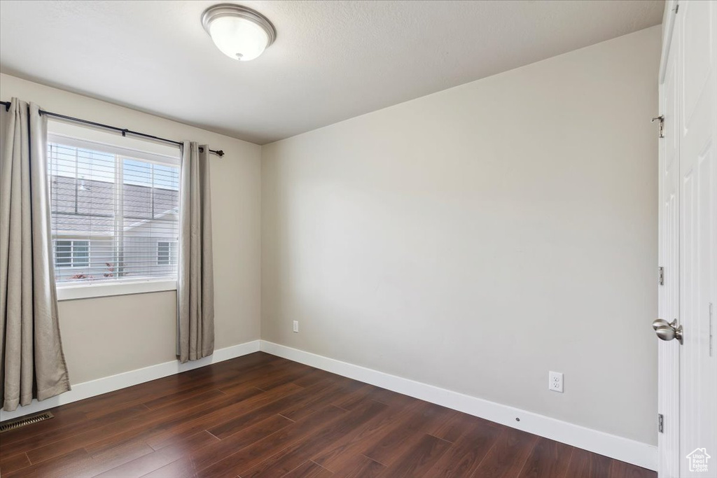 Unfurnished room with dark wood finished floors and baseboards
