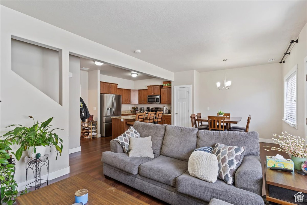 Living area featuring baseboards, an inviting chandelier, and dark wood-style flooring