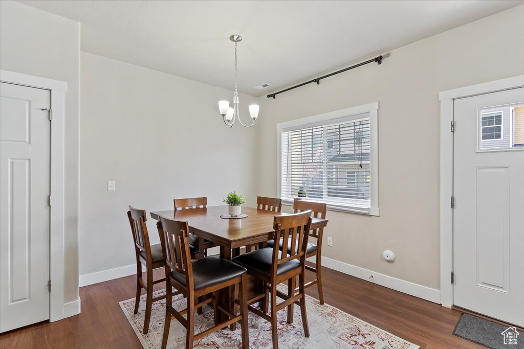 Dining room with wood finished floors, a chandelier, and baseboards