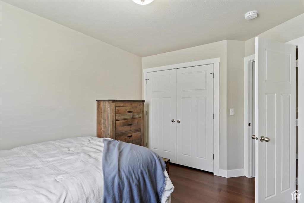 Bedroom featuring dark wood-style flooring, a closet, and baseboards