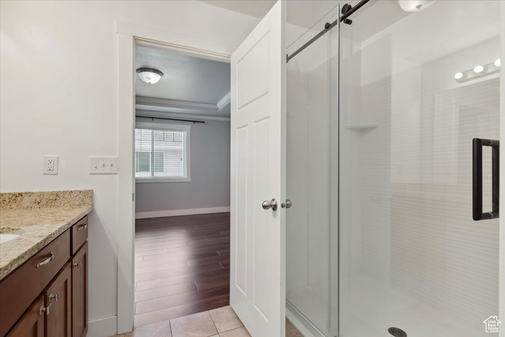 Full bath with baseboards, vanity, a stall shower, and crown molding