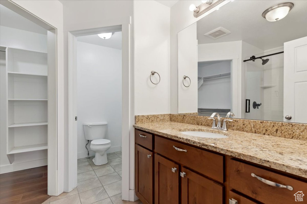Full bathroom with vanity, a walk in closet, toilet, a shower, and baseboards