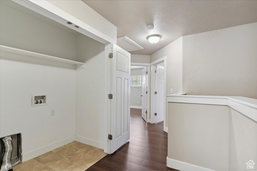 Laundry room featuring hookup for a washing machine, a textured ceiling, baseboards, and wood finished floors