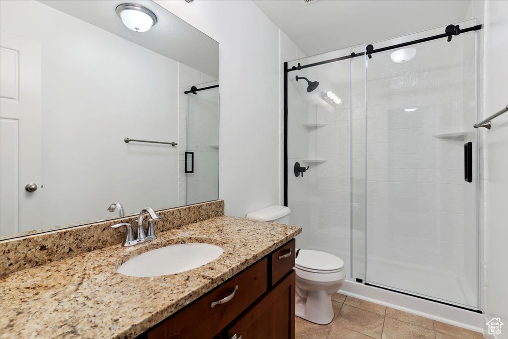 Full bathroom with a stall shower, vanity, toilet, and tile patterned floors